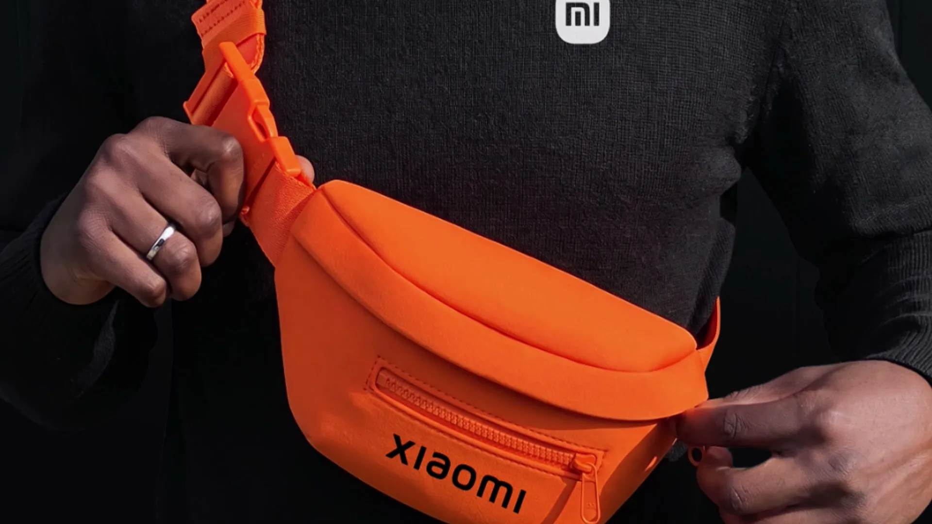 Canguro naranja con el logo de Xiaomi en manos de una persona con suéter oscuro